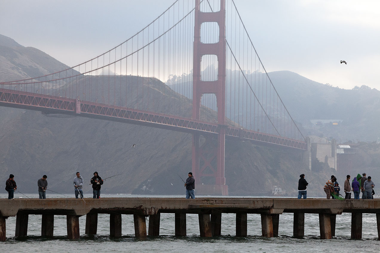 People fishing on a pier near the Golden Gate Bridge